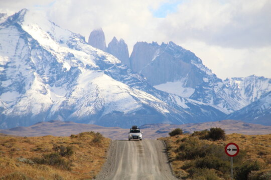 Carro em estrada na Patag&ocirc;nia chilena com as Torres del Paine ao fundo