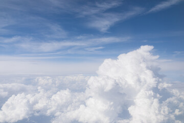 Fototapeta premium Beautiful aerial view of fluffy white clouds against a vibrant blue sky from an airplane window.