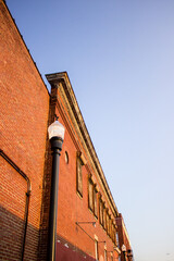 A low-angle view captures the architectural details of an aged red brick building, featuring a prominent decorative cornice and rows of boarded-up windows © Zach