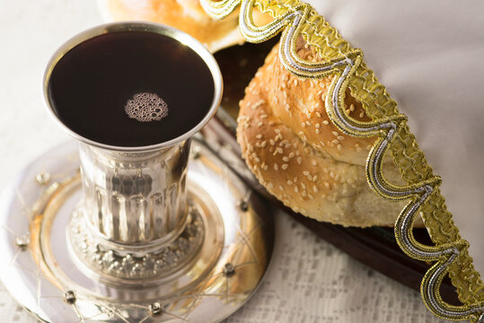 A silver Kiddush cup filled with wine alongside a Shabbat Challa (bread) 