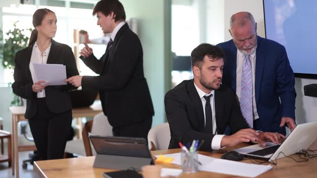  Elderly man sternly scolds adult male colleague who working on laptop in office