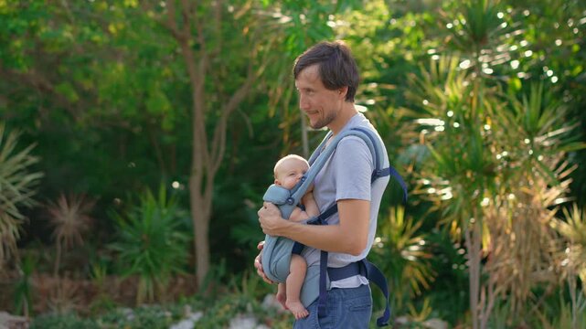 Father rocking baby son to sleep in ergonomic baby carrier. Slow motion.
