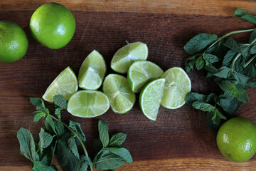 Lime wedges and fresh green mint on a wooden board. Juicy, ripe lime and aromatic mint leaves are excellent ingredients for summer lemonade. Food. Bright summer background. Citrus. Vitamins. Lime. © Татьяна Сычёва