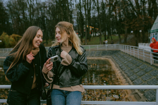 Female friends taking photos with vintage digital camera in autumn park