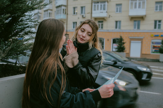 Female friends looking at paper map while traveling in rainy city