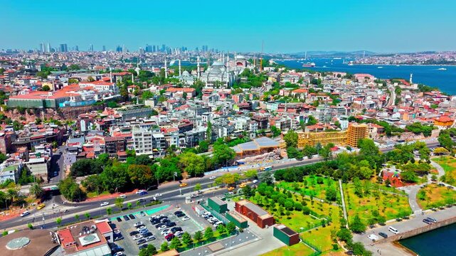 Drone view of the Blue Mosque district in Istanbul, Turkey. The Sultan Ahmed Mosque area is surrounded by dense city buildings, green spaces and distant coastline.