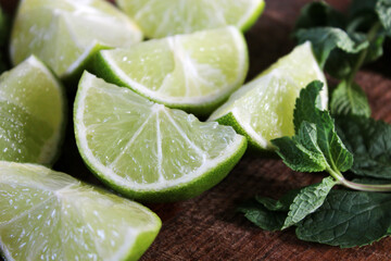 Lime wedges and fresh green mint on a wooden board. Juicy, ripe lime and aromatic mint leaves are excellent ingredients for summer lemonade. Food. Bright summer background. Citrus. Vitamins. Lime. © Татьяна Сычёва