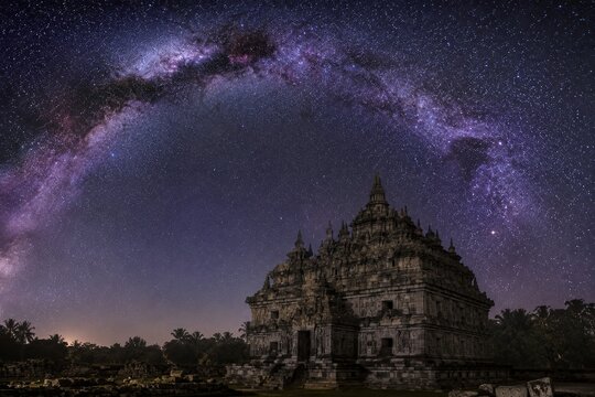 Milky Way galaxy arching over ancient Hindu Buddhist temple at night, long exposure astrophotography, Java Indonesia
