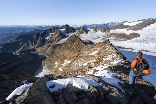 Mountaineer on a rocky ridge on the Wilder Freiger summit, behind him Signal summit and Becher summit with Becherhaus, picturesque high mountain landscape, view of &Uuml;beltalferner glacier and rocky mountain peaks K&ouml;nigshofspitz and Sonklarspitze, Stubai Alps, South Tyrol, Italy