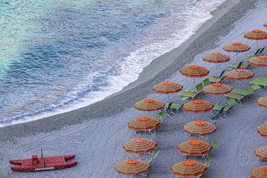 Sun loungers, parasols and red lifeboat on the beach di Fegina, Monterosso al Mare, Cinque Terre, Ligurian Coast, Liguria, Italy