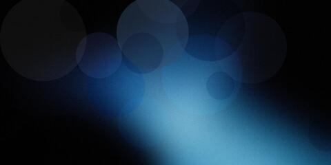 Atmospheric dark background featuring soft glowing blue circles in hazy bokeh effect over grainy black textured surface layer. © Md