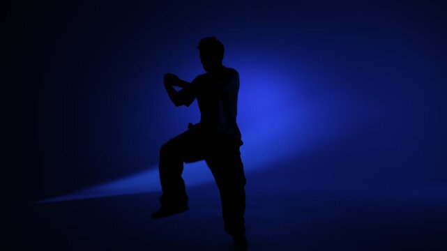 Freestyle dance pose under vivid blue studio light