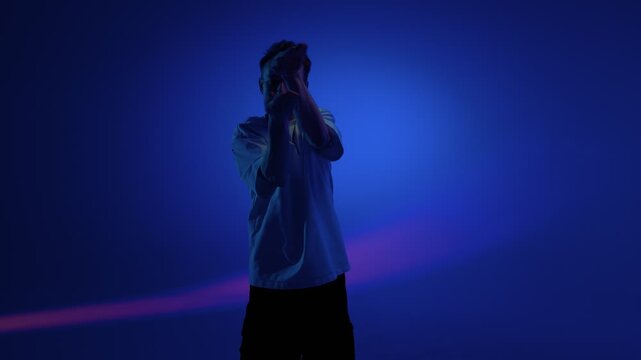 Freestyle dance pose with raised arms in blue light