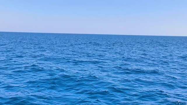 Panoramic view of the Mediterranean Sea off the coast of Cyprus, captured from a moving ship under a clear blue sky with calm waves and a peaceful summer atmosphere.