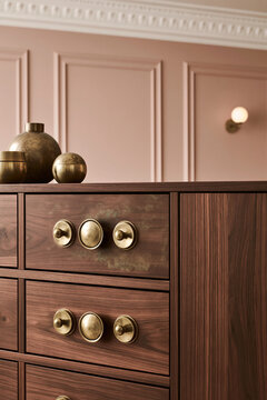 Close-up of tarnished brass hardware on walnut credenza with patina and oxidation. Soft light highlights metallic texture and depth