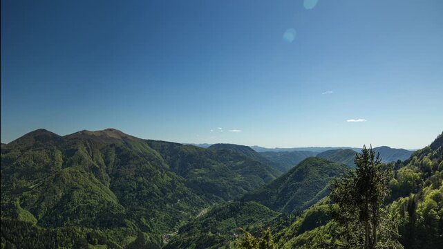 timelapse panoramico in alta quota con vista su di un ampio paesaggio tra le montagne della Slovenia, di pomeriggio, in primavera, con cielo sereno