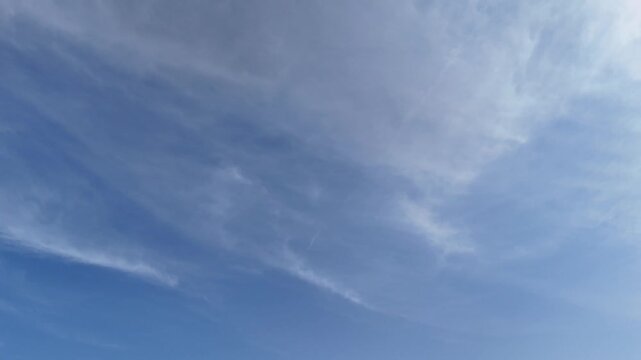 Cielo azzurro con velature sottili illuminate dal sole, che crea un bagliore morbido sulle nuvole. Scena atmosferica luminosa e serena