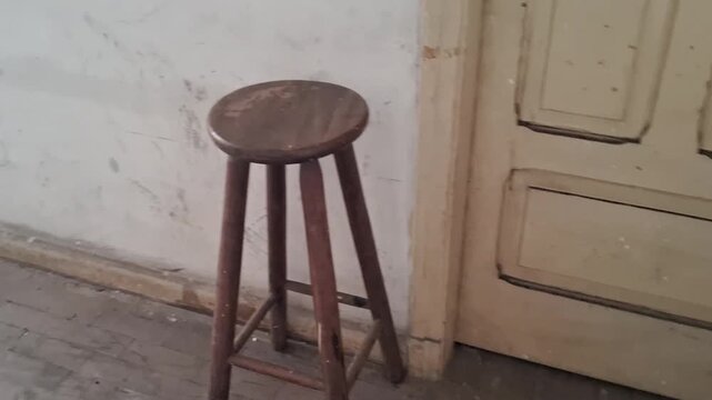 Old wooden stool standing near weathered interior doorway video footage