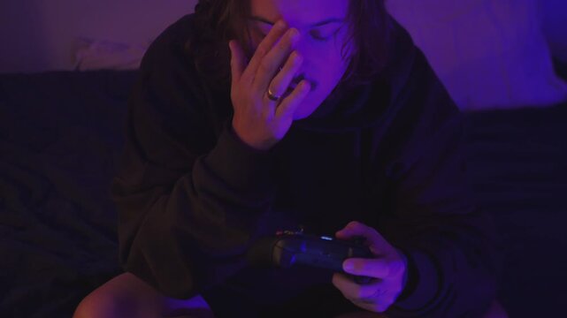 Young Man Gaming with Controller in Purple Neon Bedroom, Overhead View