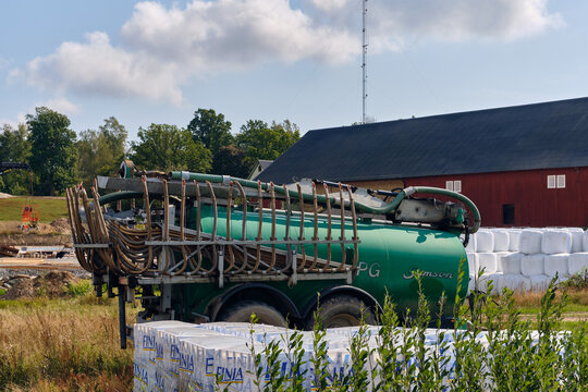 Agricultural machinery and farm construction, flatbed truck with hydraulic crane hoisting a high reach lift on a building site in Torp, Sweden