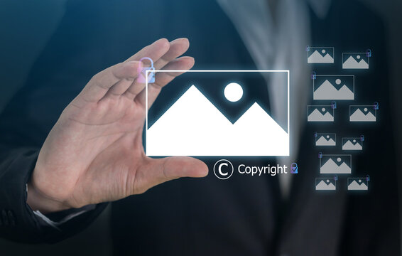 Businessman holding virtual copyright icon and photo hologram, Intellectual property protection, digital asset licensing, stock photo video rights and creative content legal ownership system