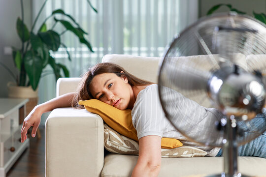 Exhausted woman lying on sofa during heatwave