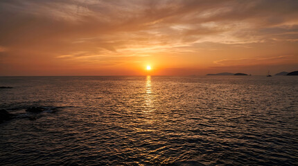 Fototapeta premium Sunset over calm ocean water with distant islands and warm orange sky