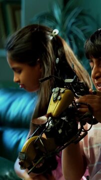 Indian Asian small sibling kids fighting over toy bike while sitting on sofa in modern home interior, one child upset while brother and sister argue, family bonding, sibling rivalry