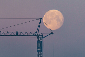Księżyc w pełni nad konstrukcją dźwigu na tle wieczornego nieba w odcieniach fioletu i różu. © Henryk Niestrój