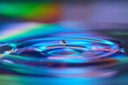Water drop ripple on blue green iridescent disc