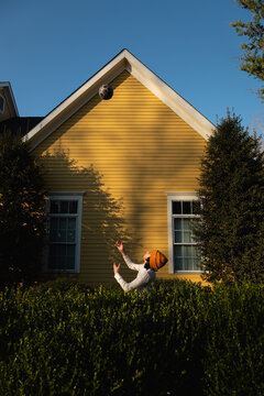 A teenage boy playing with a ball in front of of yellow house