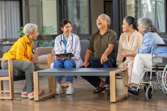 Senior doctor wheelchair caregiver group healthcare consultation with elderly patient in care home lounge warm conversation support recovery