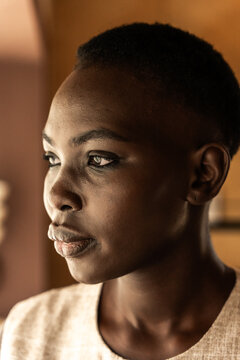 Woman Looks Thoughtfully While Standing Indoors in Natural Light