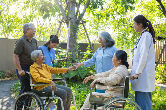 Senior caregiver wheelchair doctor garden patient elderly healthcare greet with warm support during outdoor care meeting in green courtyard