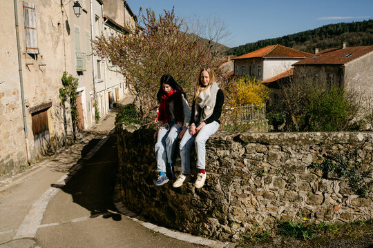 two young women climbing a wall  in village in the South of France