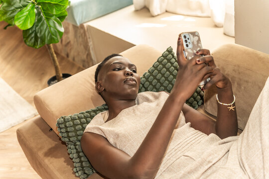 Woman Using Smartphone While Relaxing on Couch in Modern Room
