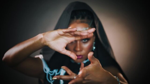 Closeup fantasy african american woman voodoo witch conjuring. Art dance hands. Girl vampire dances hypnotizes with finger slow motion. sexy face. Gothic style Black dress hood vertical video crop.