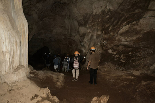an interior view showcasing the immense scale and raw adventure of exploring the vast, dark limestone cavern of khao wang thong cave in thailand