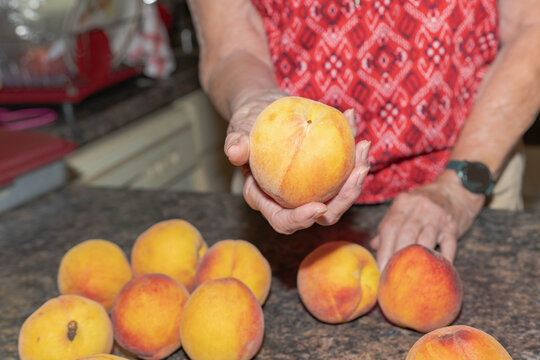 Elderly woman holding a fresh, ripe, peach in her hand.  Senior's making healthy eating choices concept.