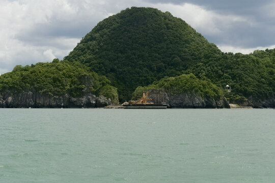 lush limestone hills rise above the calm waters of the khanom coastline in southern thailand beneath a dramatic cloudy sky