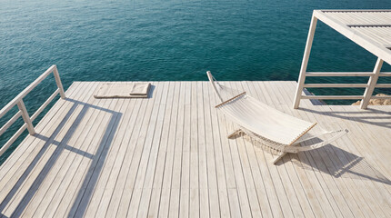 Fototapeta premium Top-down view of a white hammock on a wooden deck by turquoise sea providing copy space for luxury travel advertising.