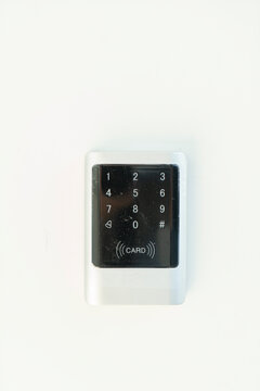 Minimalist front view of a digital security keypad and contactless RFID card reader mounted on a plain white wall for electronic access control in offices or modern homes