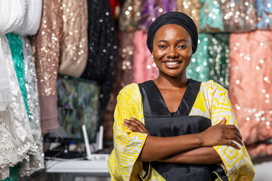 Smiling african woman entrepreneur, small business owner standing with arms crossed in her textile shop