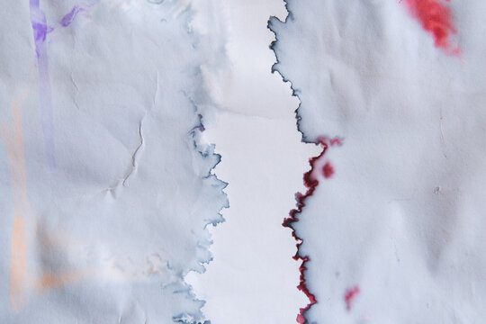 White paper stained with blue and red ink on left and right side with narrow empty space in the middle