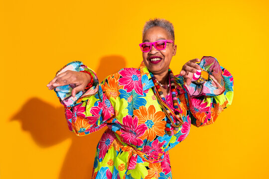 Senior woman dancing with joy and colorful dress - Old hispanic grandmother wearing fashionable modern clothing on colorful background, concepts about elderly, aging, diversity 