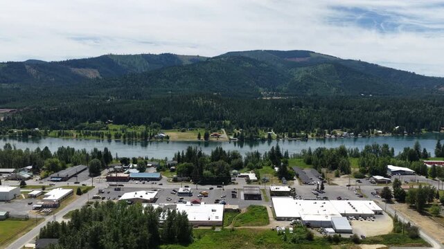 Aerial of Priest River small mountain town with riverfront community and mountain backdrop in summer