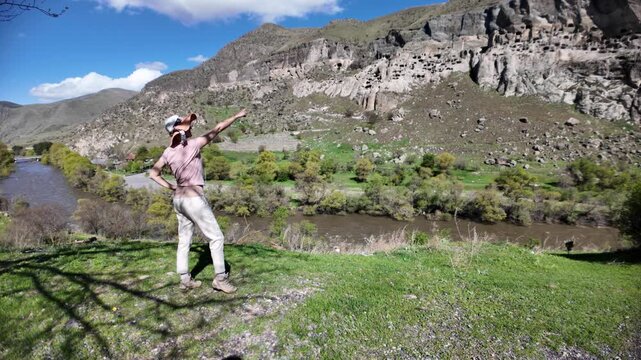 tourist woman by the Kura River. Observing the ancient Vardzia cave monastery complex carved into the Erusheti Mountain in Samtskhe-Javakheti region. Representing a blend of travel. History in Georgia