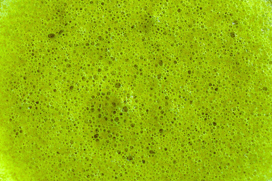 Extreme close up of bright green matcha latte foam surface texture filling entire frame, vivid green color with dense bubble pattern, suitable as background for text and lettering overlay