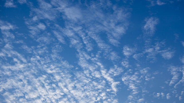 Blue sky with scattered white cirrocumulus clouds on a sunny day