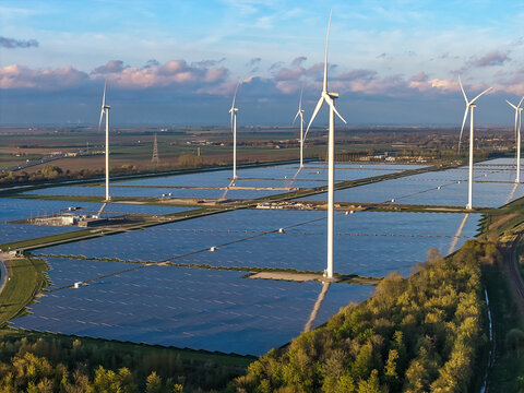 Aerial view of a large solar farm integrated with wind turbines in the rural landscape of Groningen, Netherlands.